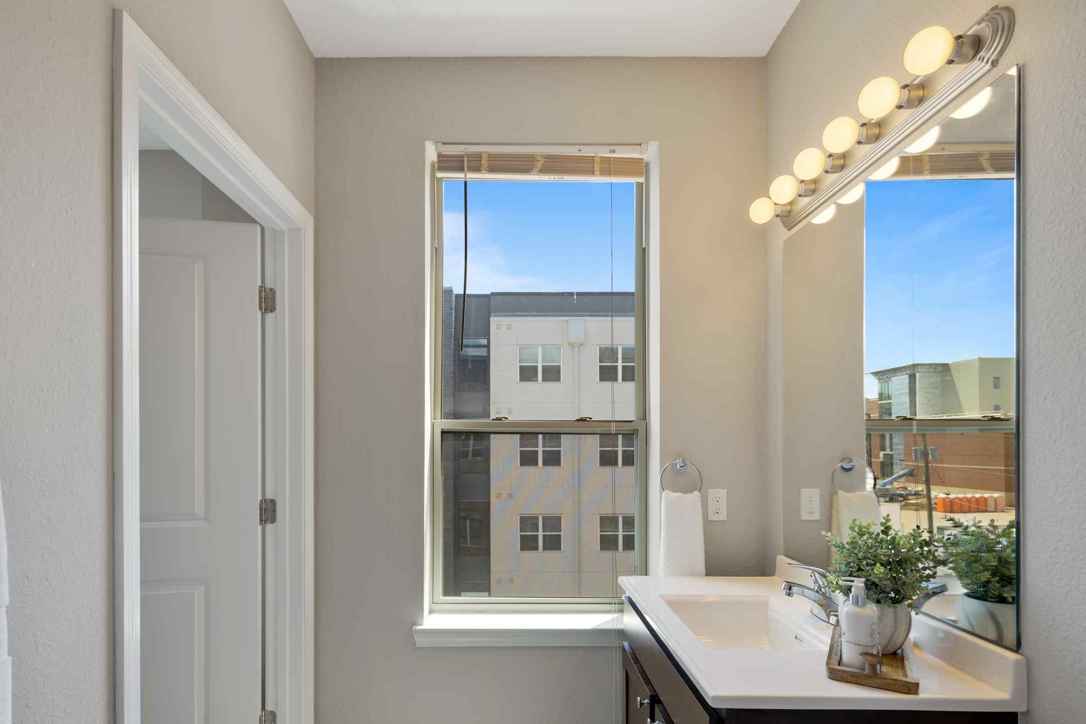 A tidy student housing apartment bathroom with a sink and a window.