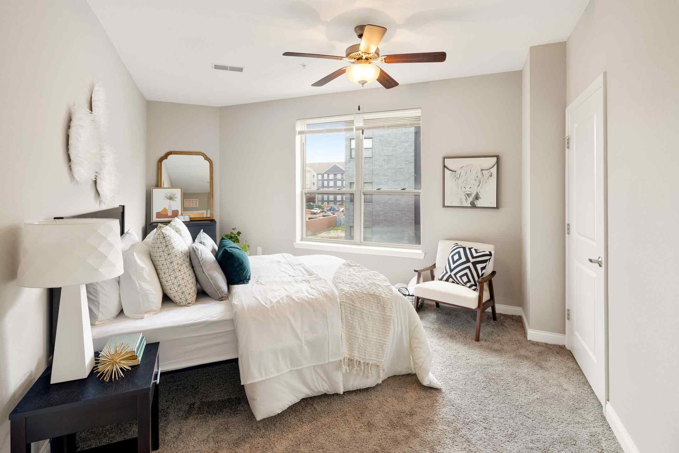 A cozy student housing bedroom with a ceiling fan and a neatly made bed. Perfect for studying and relaxing.