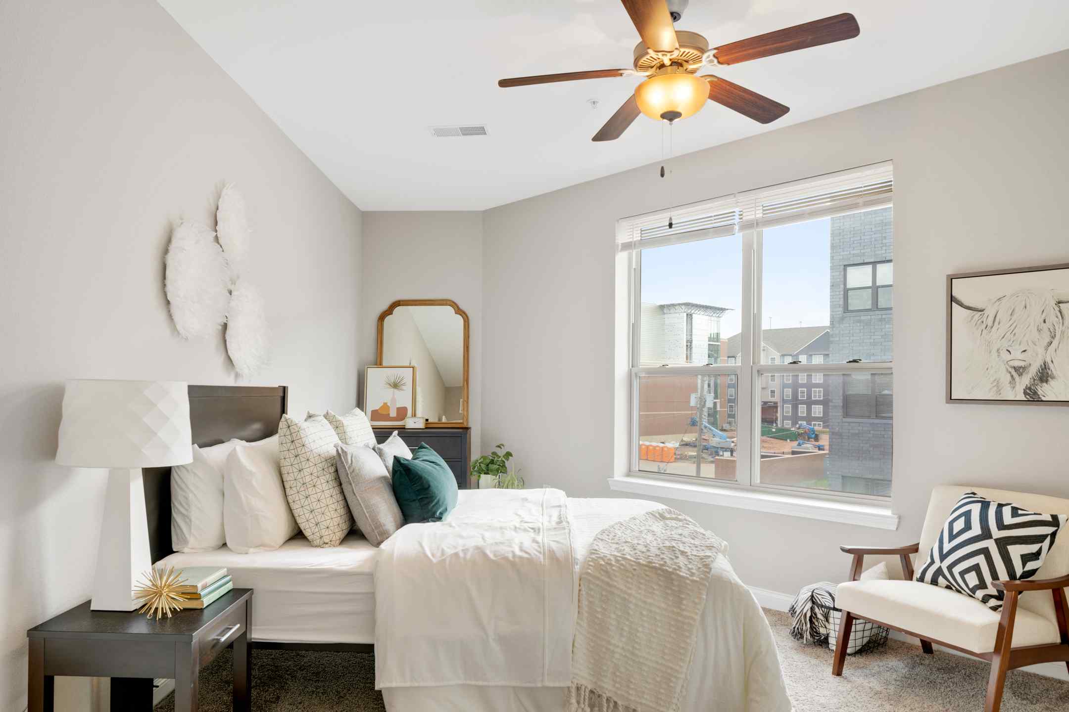 A cozy student housing bedroom with a ceiling fan and a neatly made bed. Perfect for studying and relaxing.