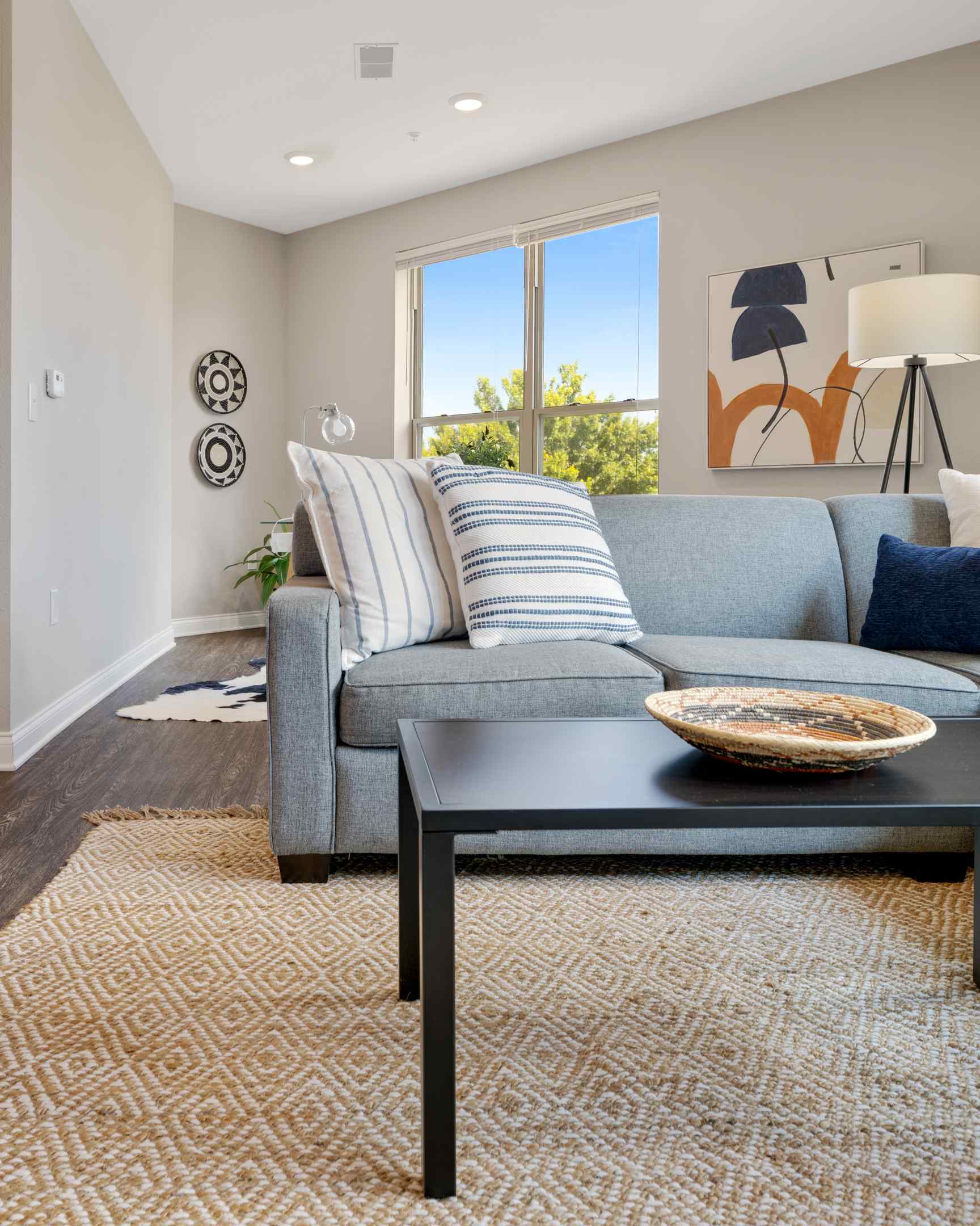 A cozy student housing apartment living room with a comfy couch, a coffee table, and large windows.