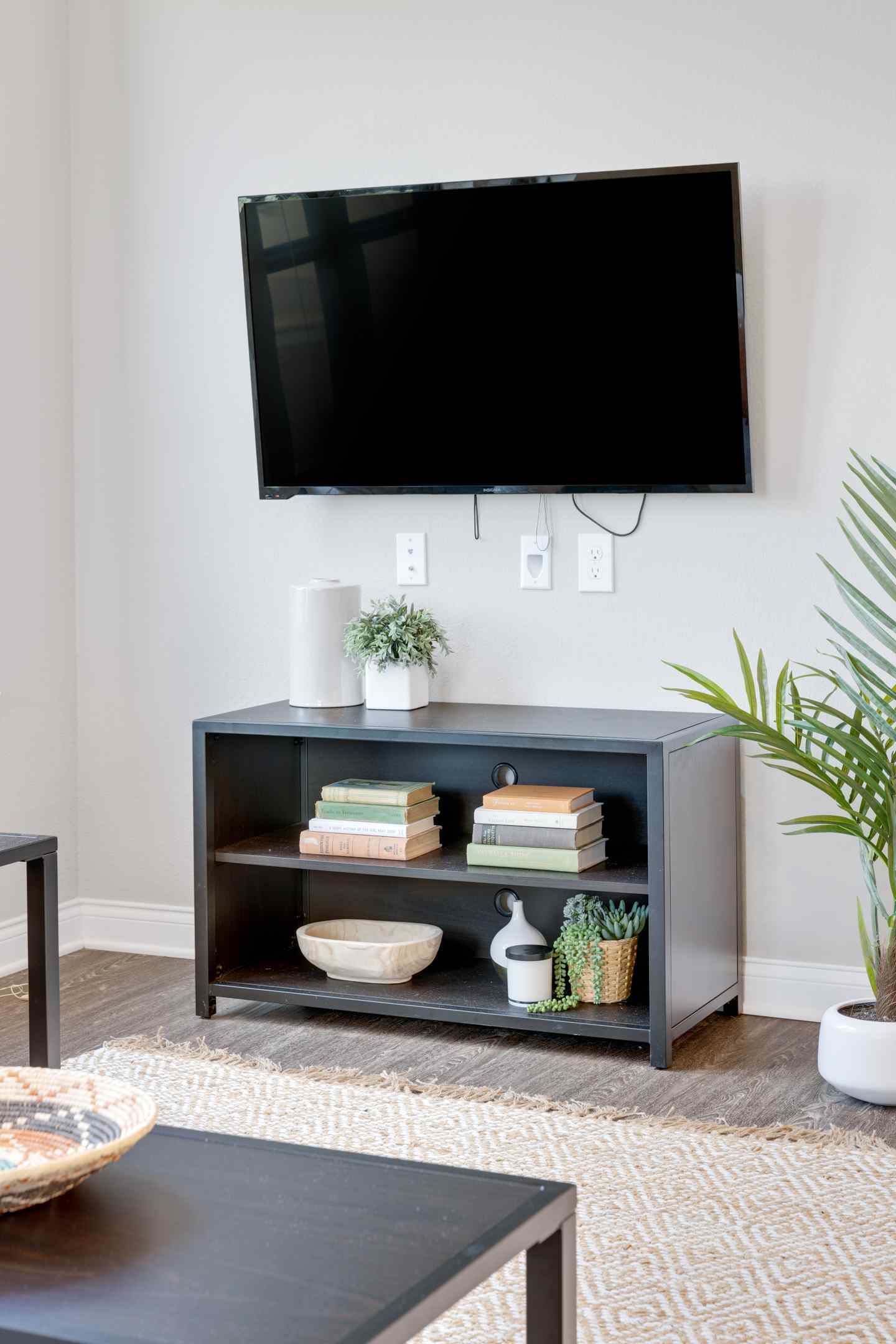 A cozy student housing apartment living room, zoomed in on the media stand and mounted flat screen tv.