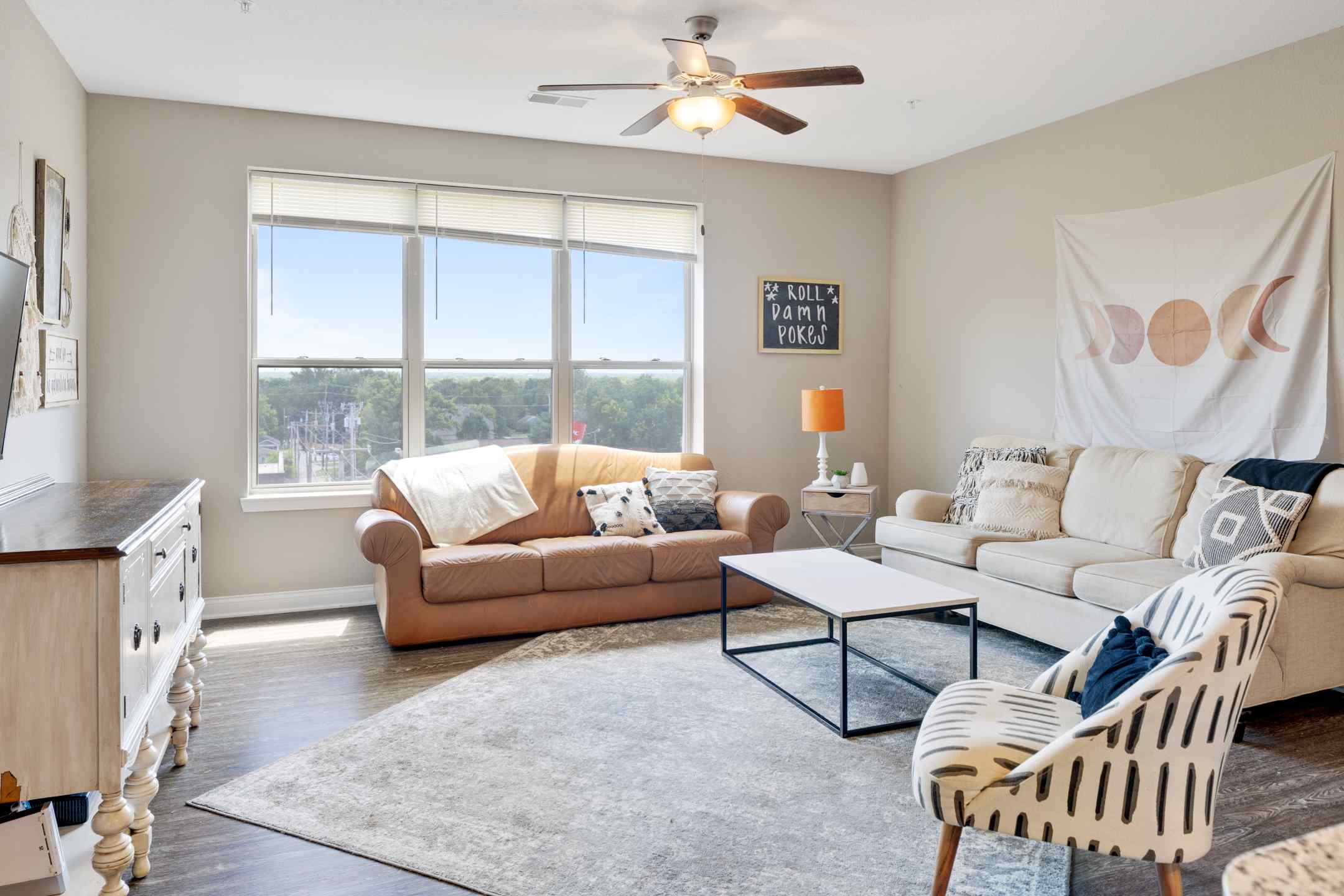 Student housing apartment living room with leather couch, coffee table, and wall art.