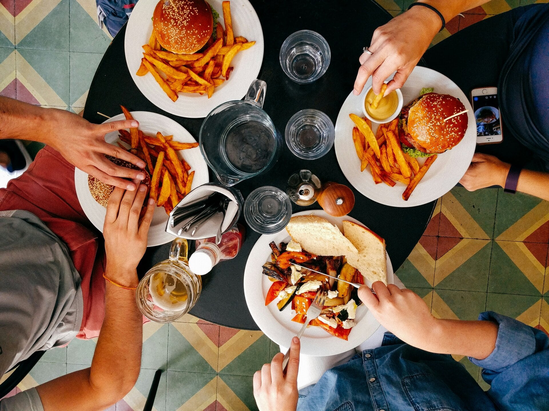 A diverse group of friends enjoying a meal together at a table filled with delicious food.